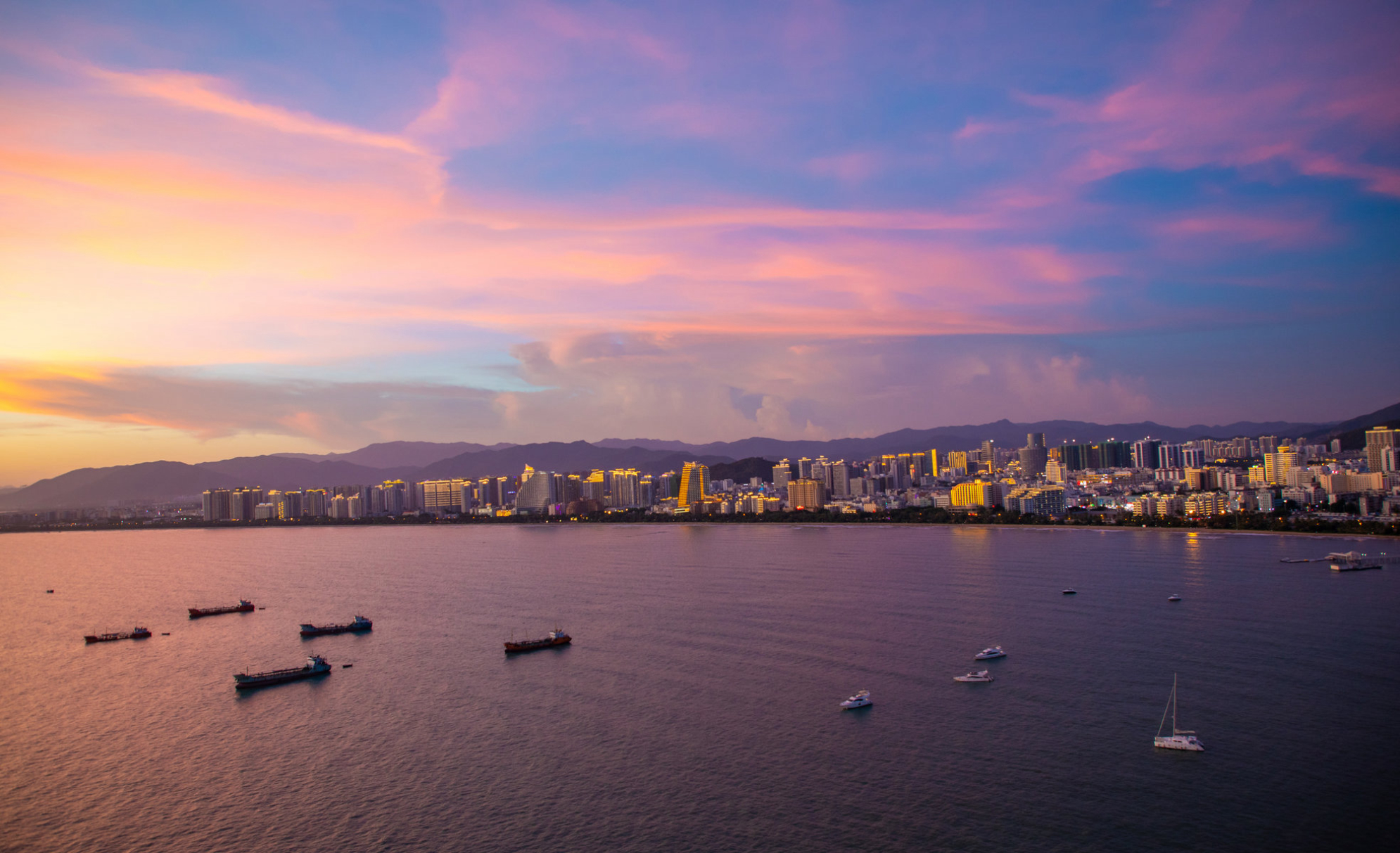 Вечерний городской пейзаж города Санья, вид с острова Феникс на острове Хайнань в Китае. Источник: Shutterstock
