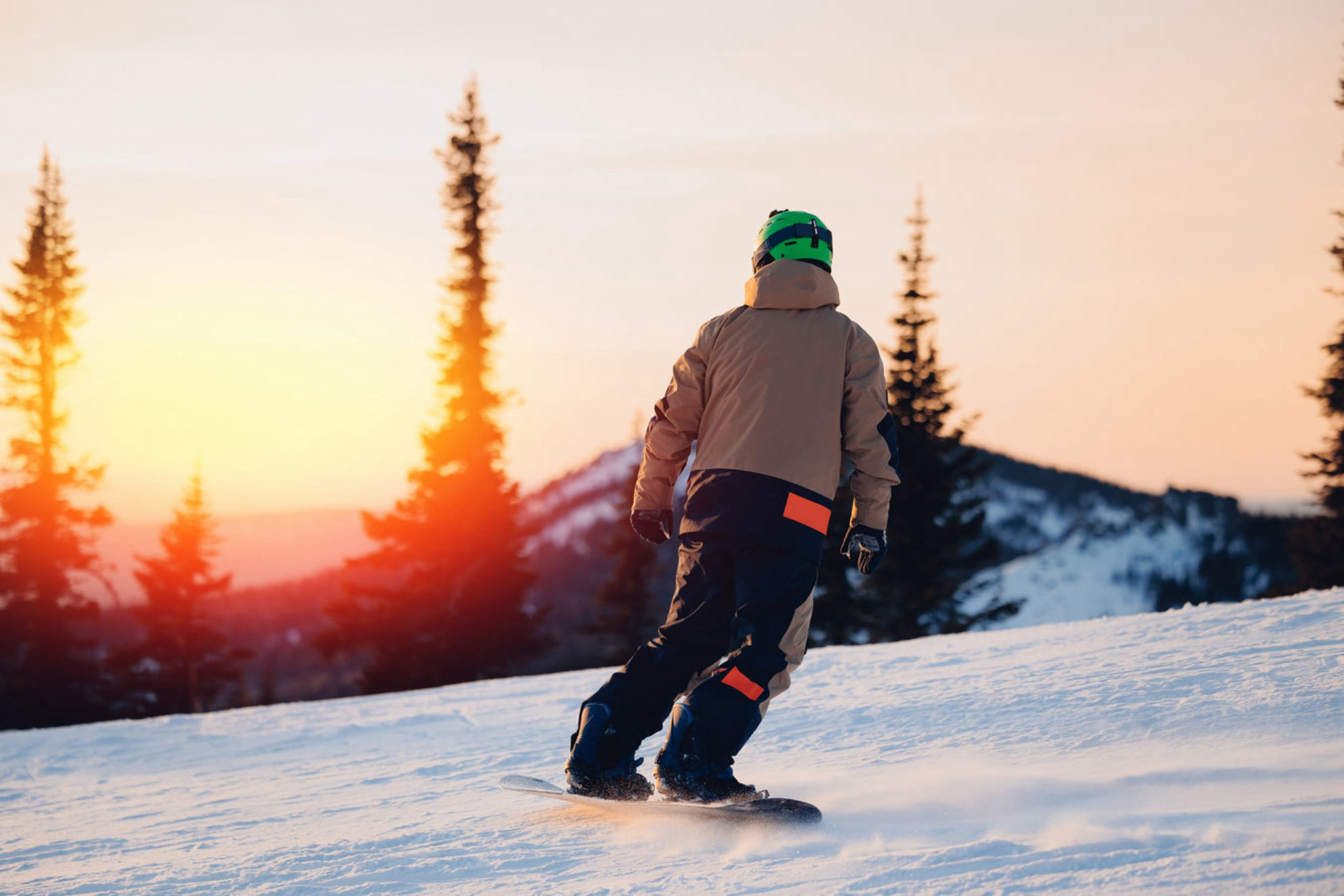 Сноубордист, занимающийся экстремальными зимними видами спорта на фоне заснеженного леса. Shutterstock.com