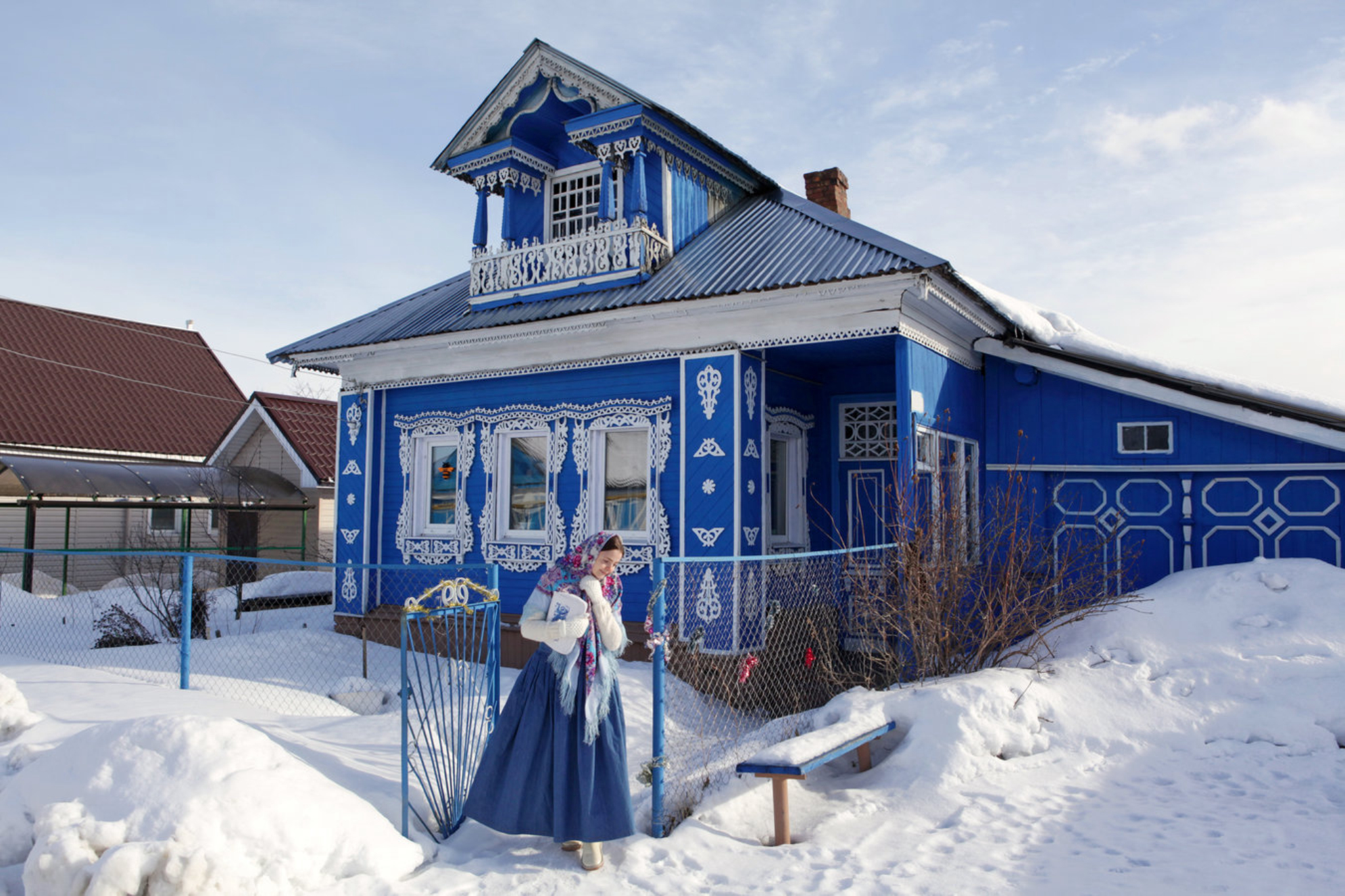 Русская девушка в павловопосадской шали на фоне деревянного дома с резными окнами. Нижегородская область, Россия. Shutterstock