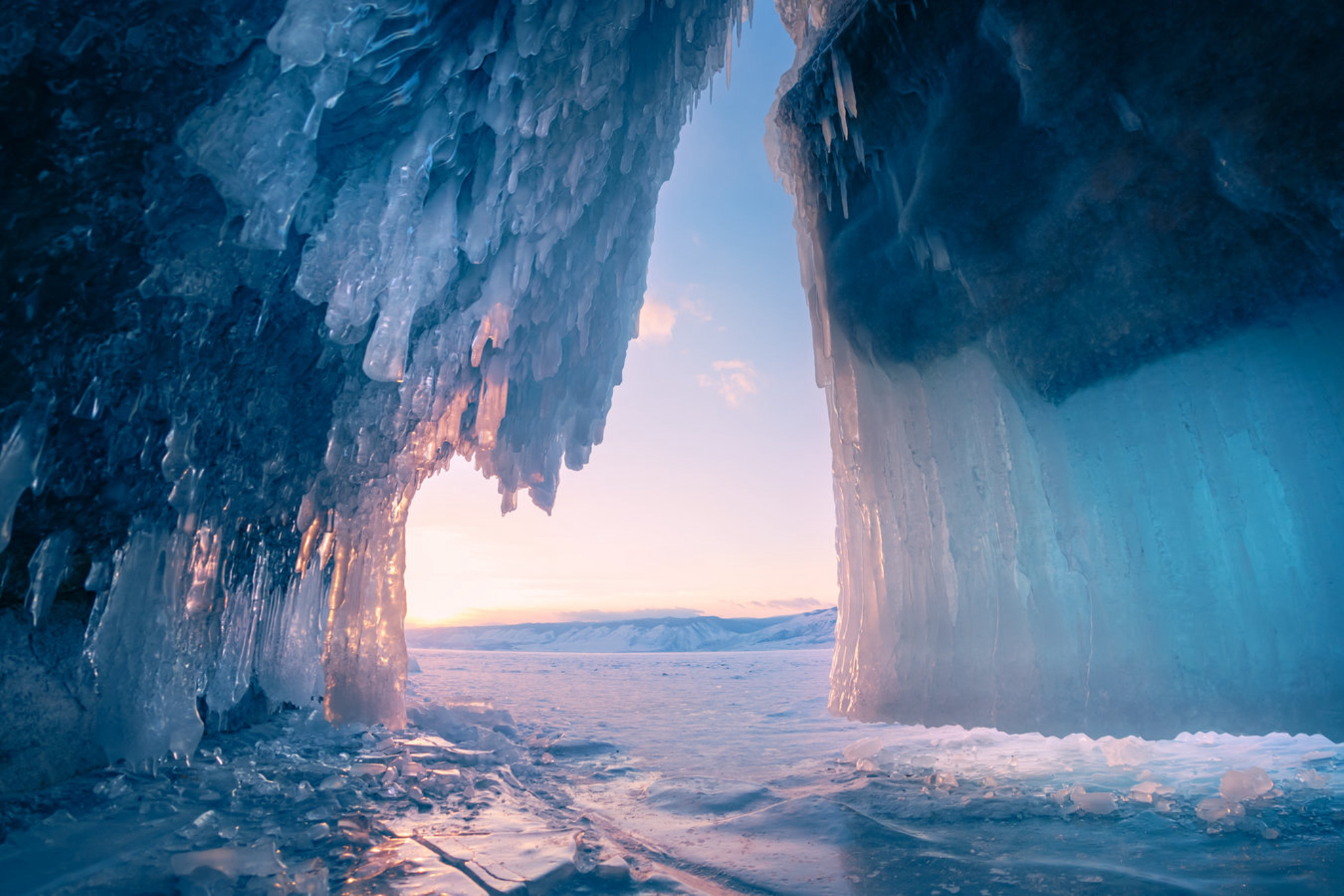 Ледяная пещера с сосульками на озере Байкал на закате. Зимний пейзаж озера Байкал, Сибирь, Россия. Shutterstock