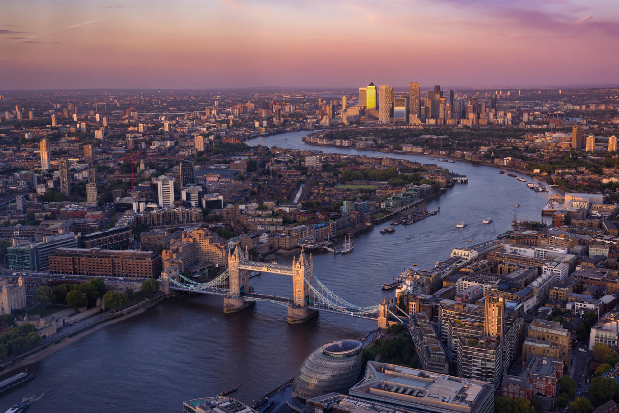 Красочный вид на закат над Тауэрским мостом и горизонтом Лондона вдоль реки Темзы до Кэнэри-Уорф, финансового района Англии Shutterstock