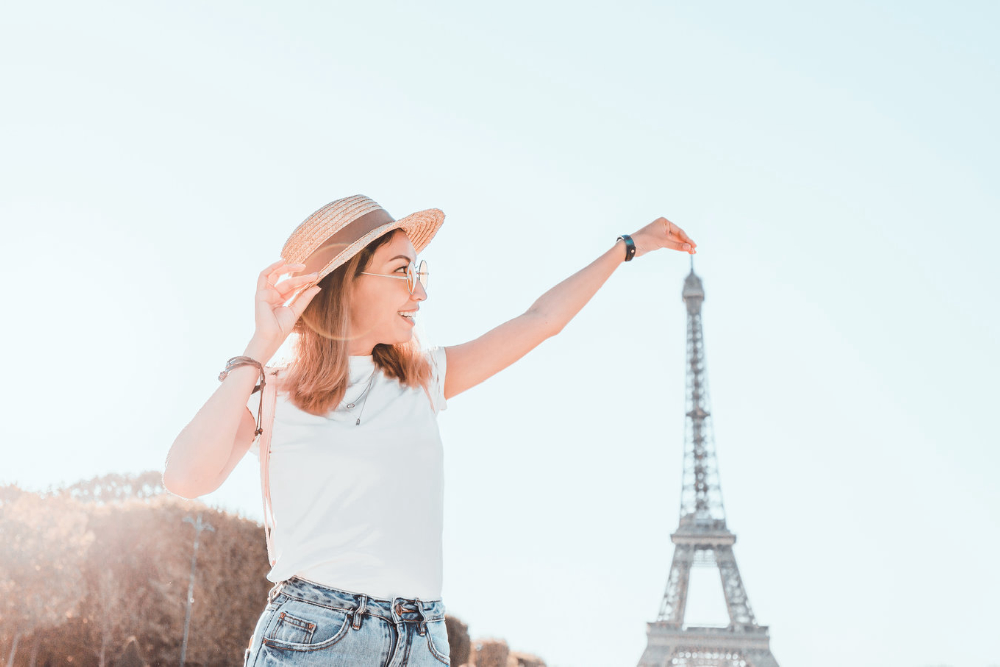 Счастливая путешественница позирует на фоне величественной Эйфелевой башни Shutterstock
