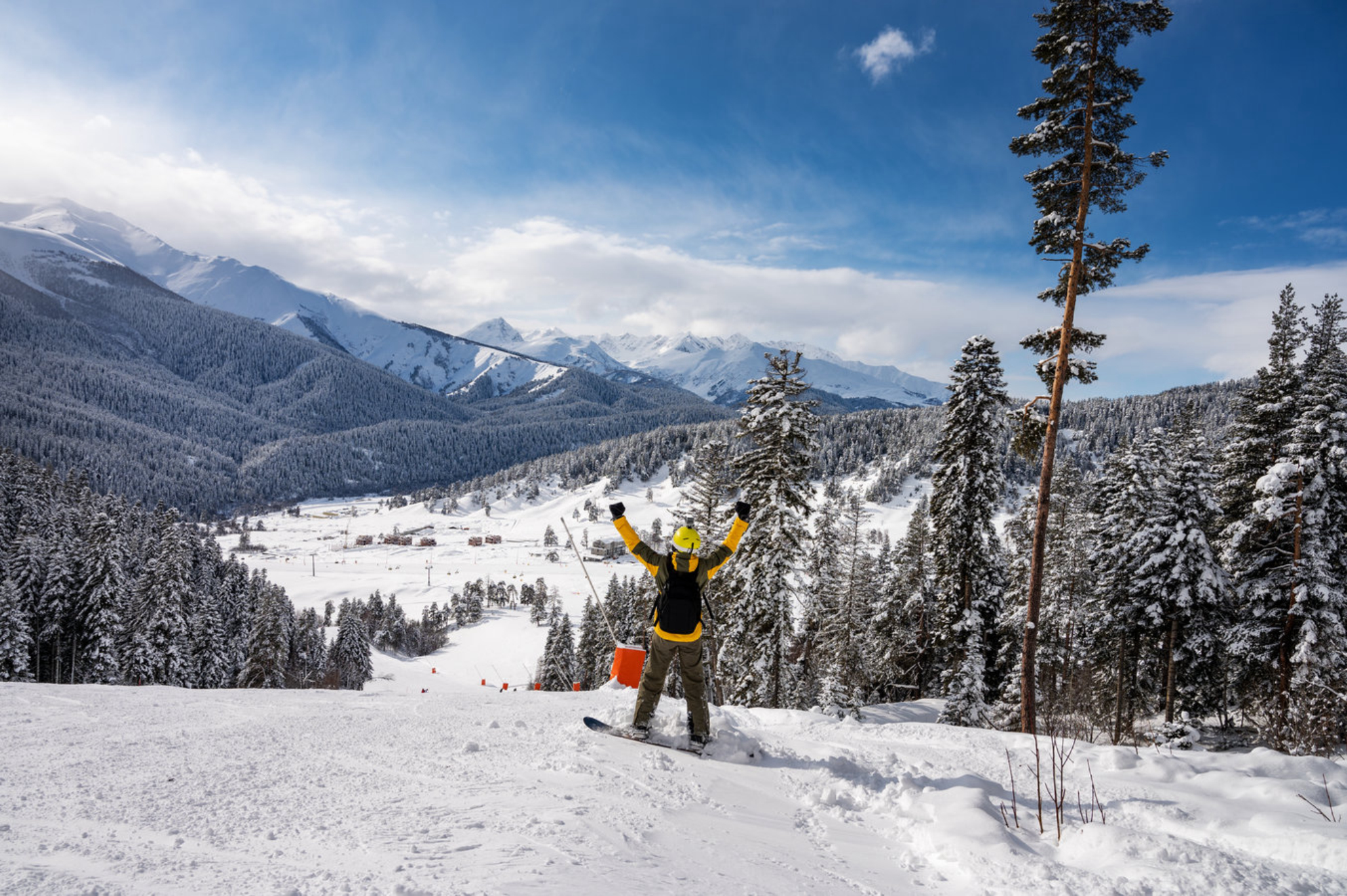 Красивый пейзаж горнолыжного курорта Архыз с горами, снегом, лесом и сноубордистом в солнечный зимний день. Горнолыжный курорт Архыз, Карачаево-Черкесская республика. Источник: Shutterstock