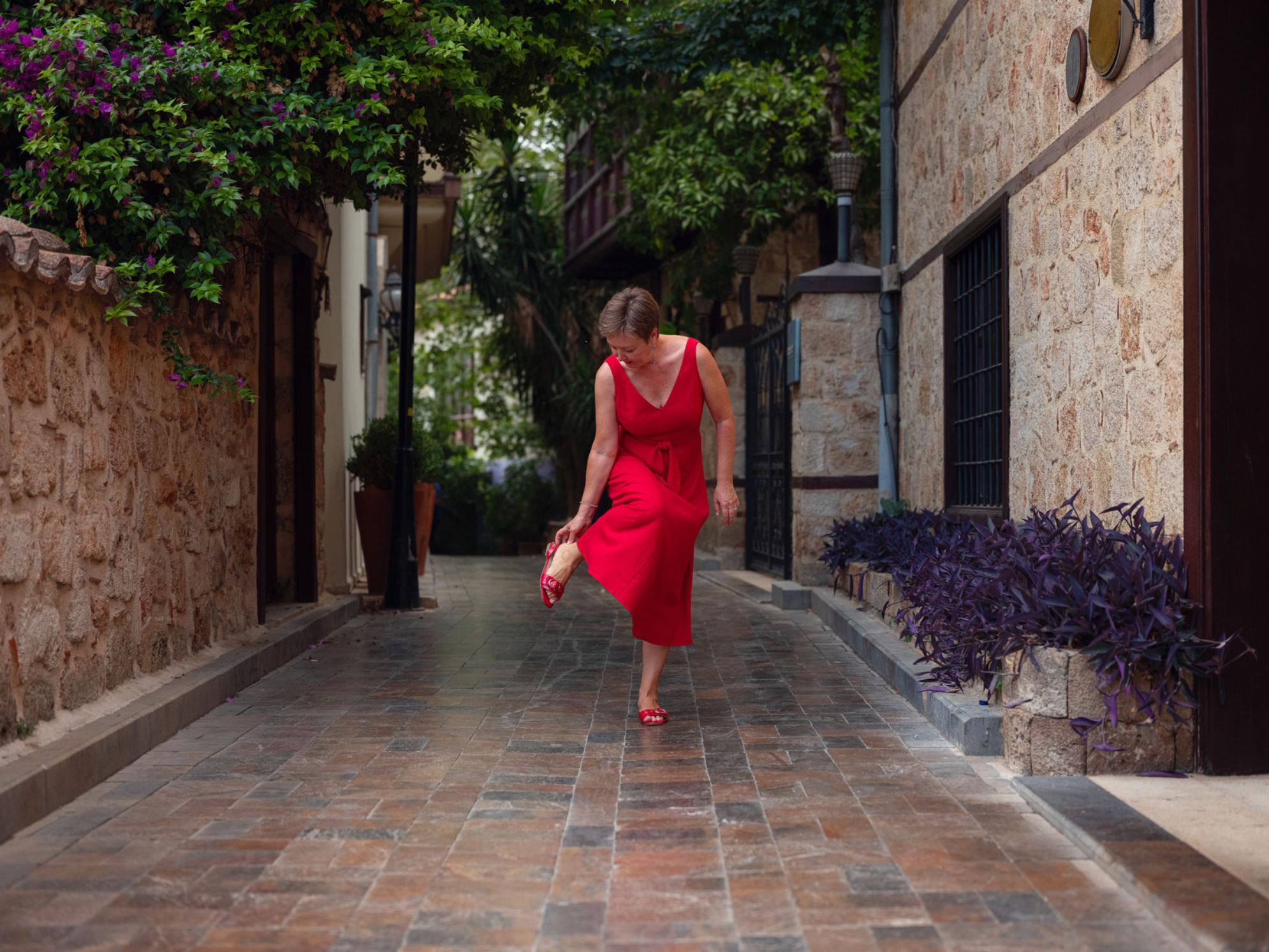 Женщина в красном платье гуляет по узким улочкам Старого города Антальи теплым летним вечером. Источник: Shutterstock