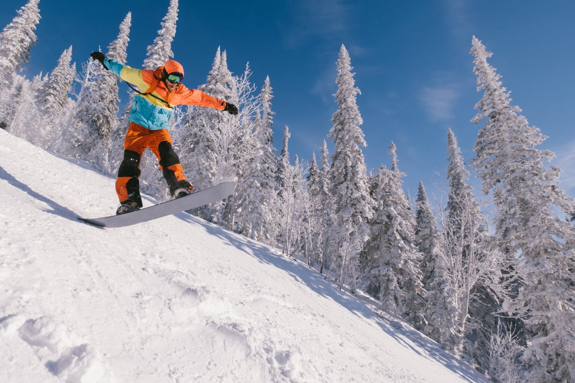 Мужчина прыгает на сноуборде по заснеженной трассе в Шерегеше. Shutterstock.com