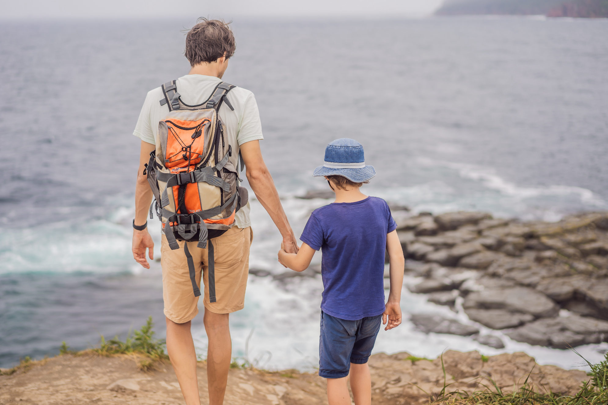 Папа с сыном на фоне скал и Японского моря, остров Русский. Источник: Shutterstock